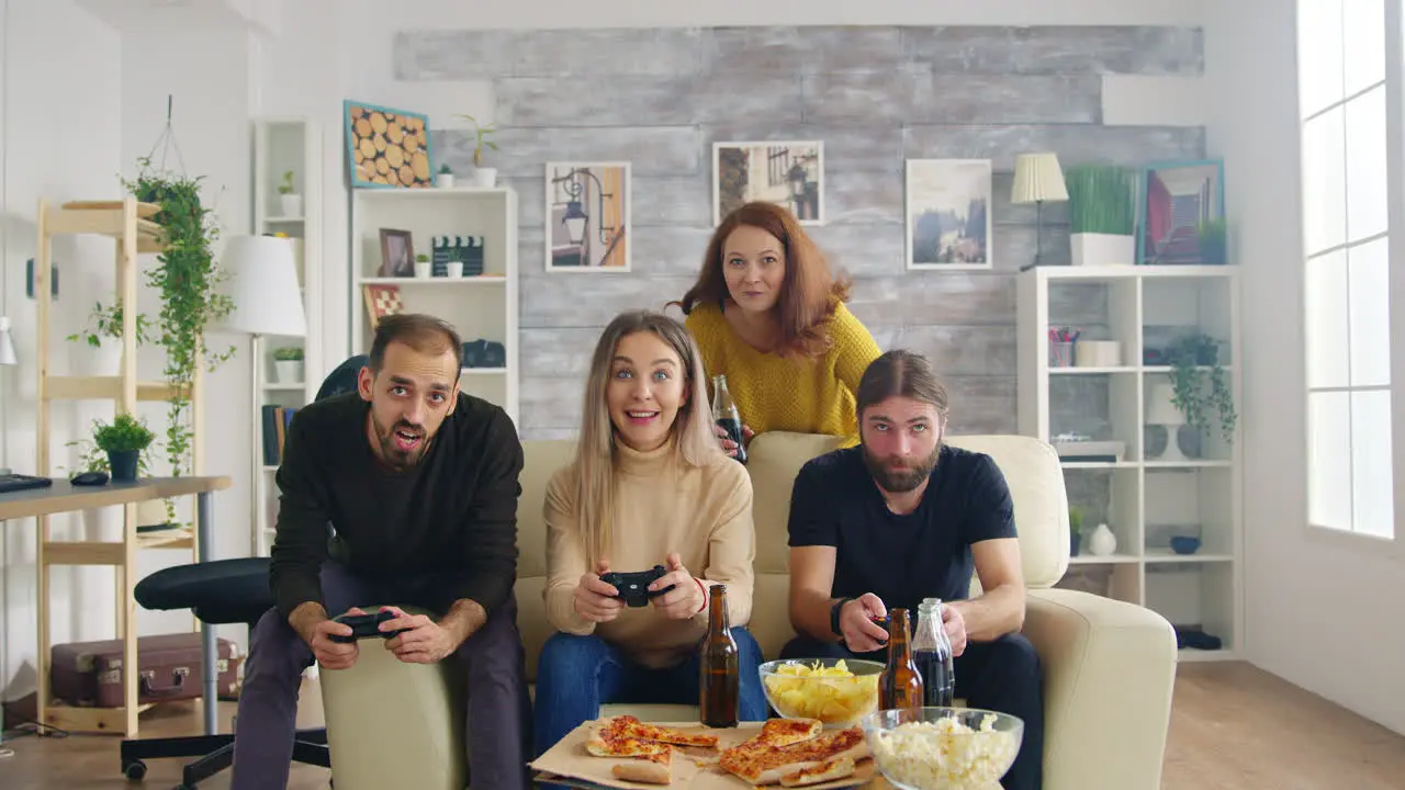 Group of friends relaxing together in living room playing video games