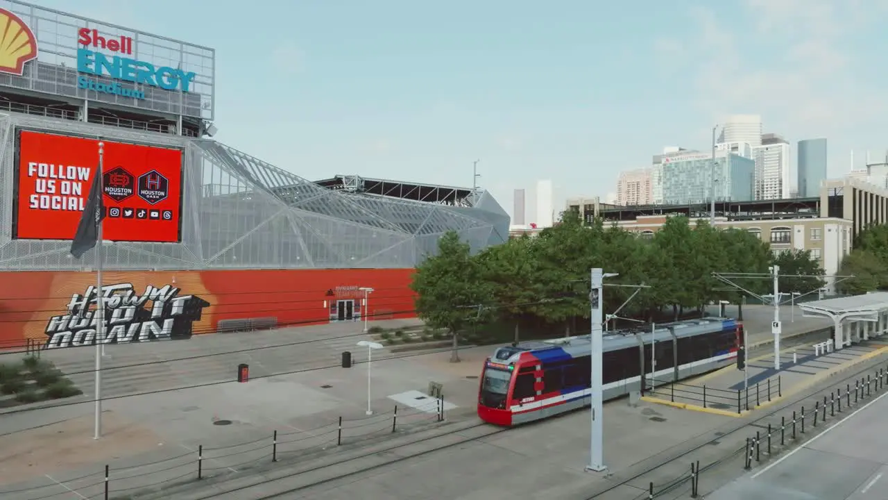 Aerial drone view of a Houston Metro Train passing in front of the Shell Energy Stadium in downtown Houston Texas