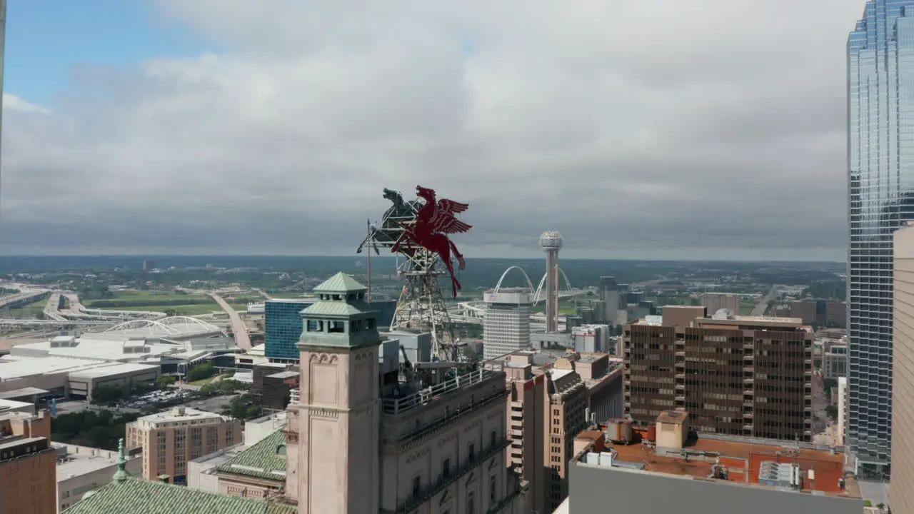 Forwards ascending fly to Pegasus on roof of Magnolia Building Two massive red sculptures on top tall building Dallas Texas US