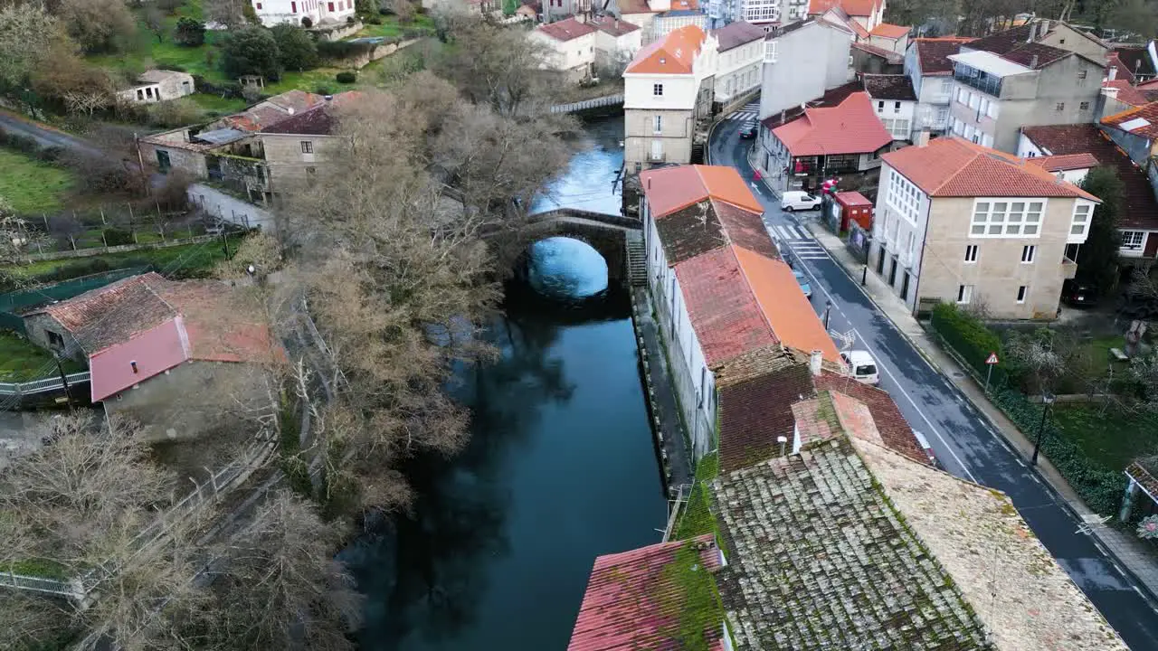 Drone dolly aerial of River Molgas and roman bridge crossing water reflection of trees and sky