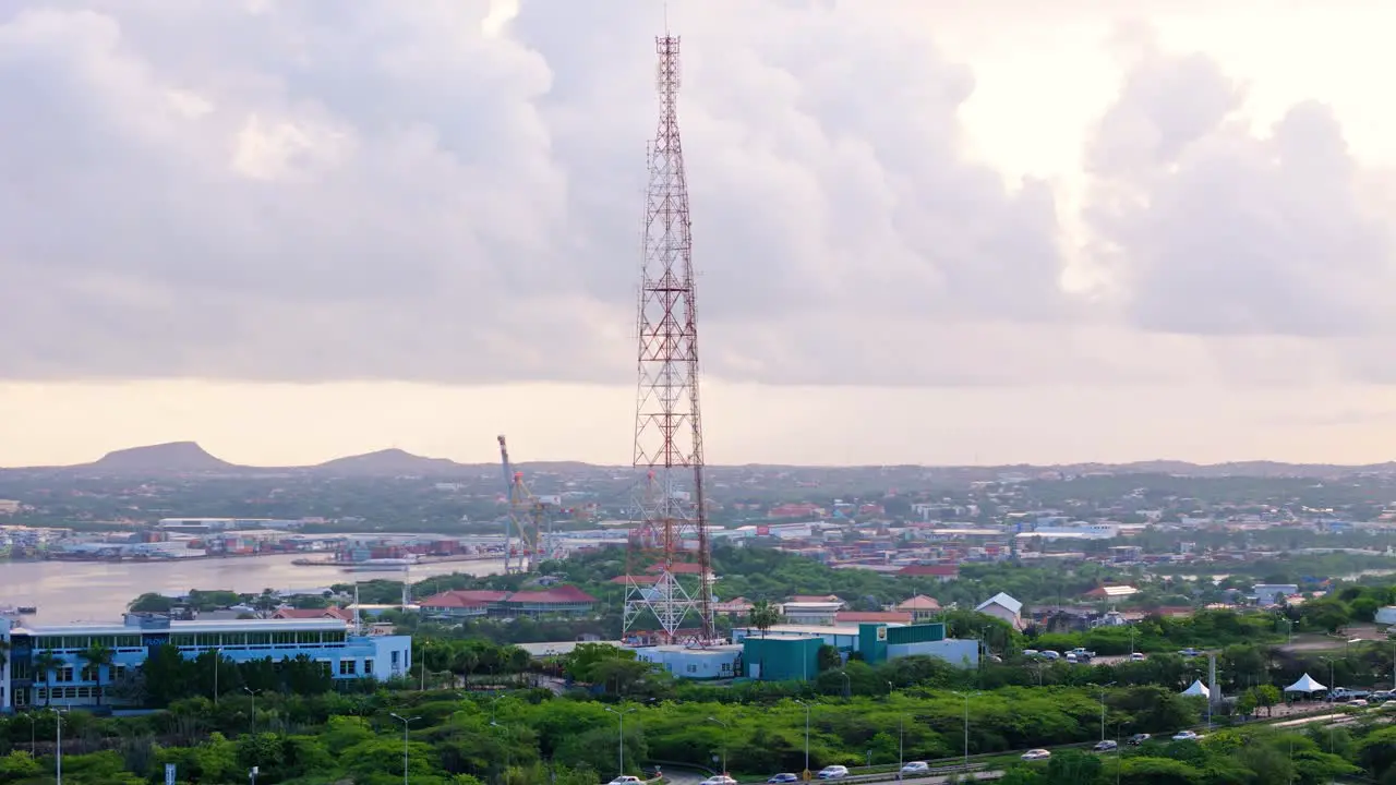 Large telecommunications tower stands tall against Curacao towns and cloudy sky