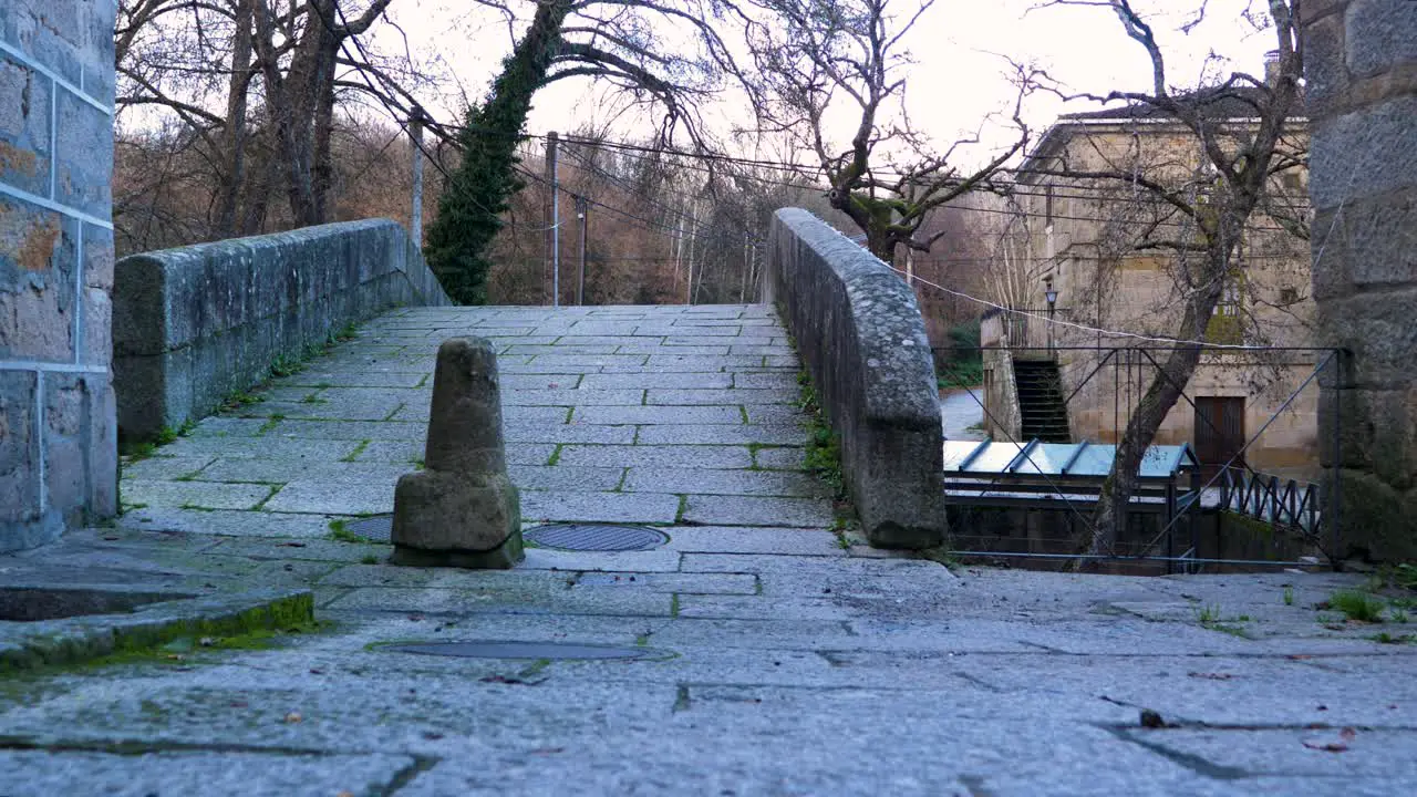 Low angle view of granite pathway with grass growing through crack of Roman bridge