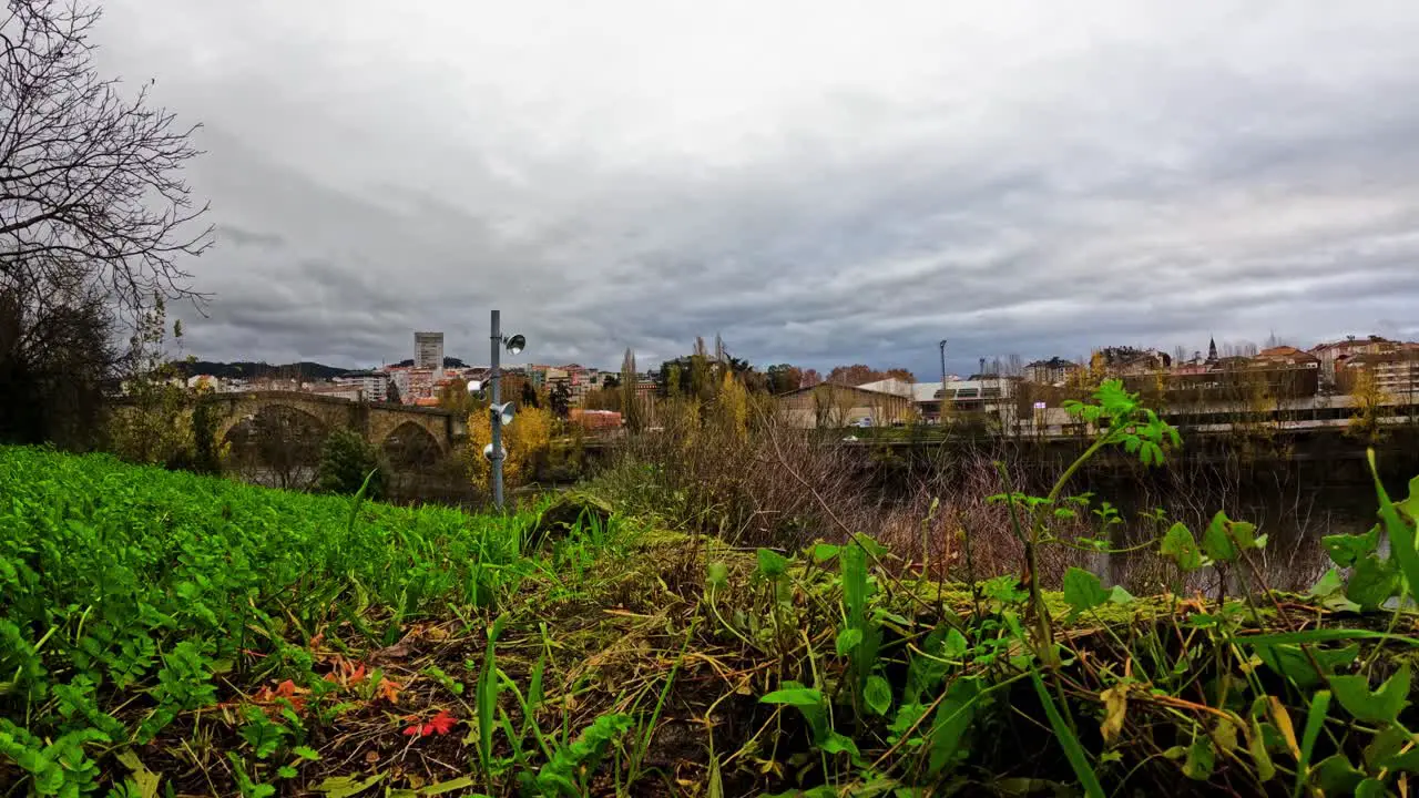 Timelapse of Roman bridge Mino River and road way entering Ourense as clouds rush in sky