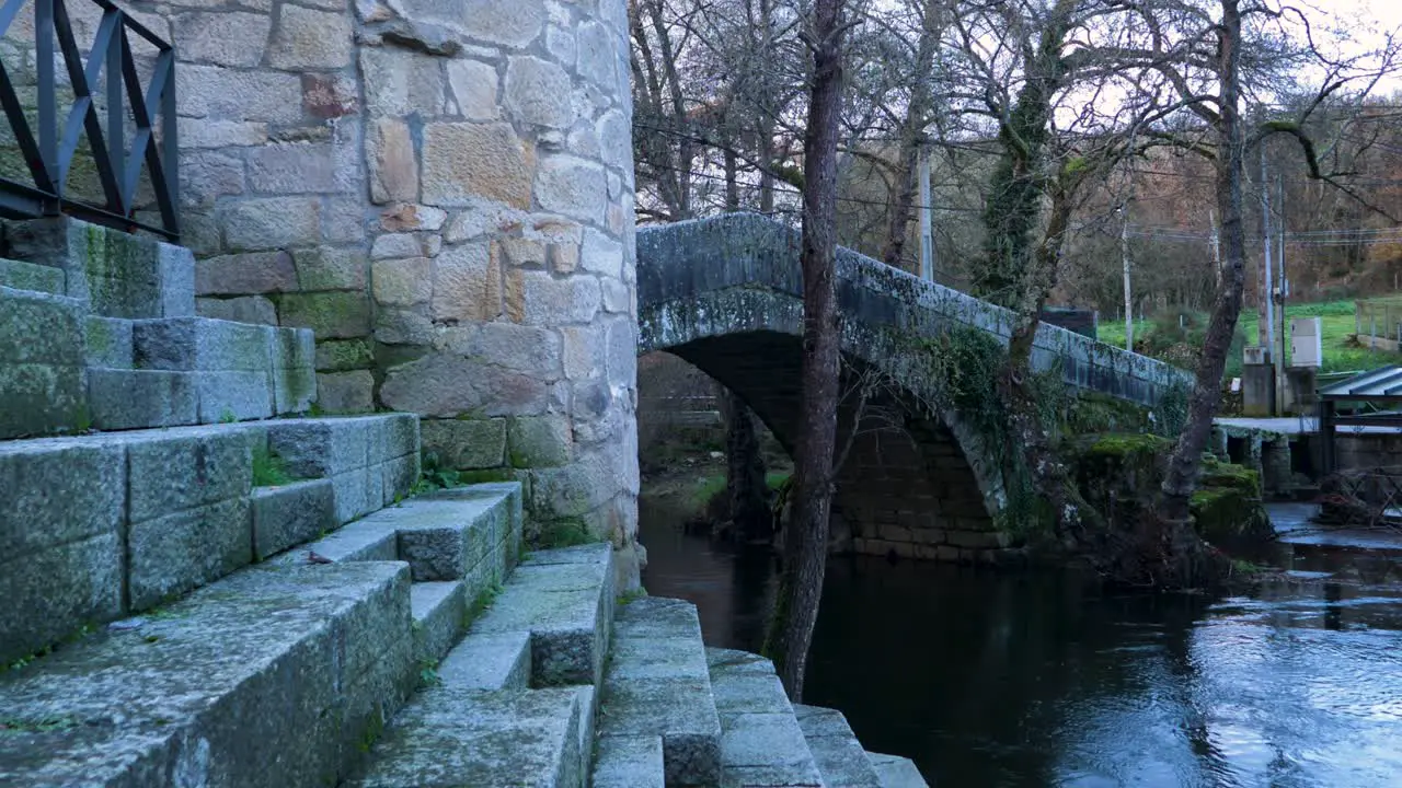 Precise carved stone granite steps lead to river Molgas with Roman arched bridge