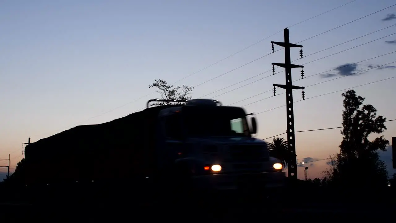 A truck and a car pass by on a route at dusk