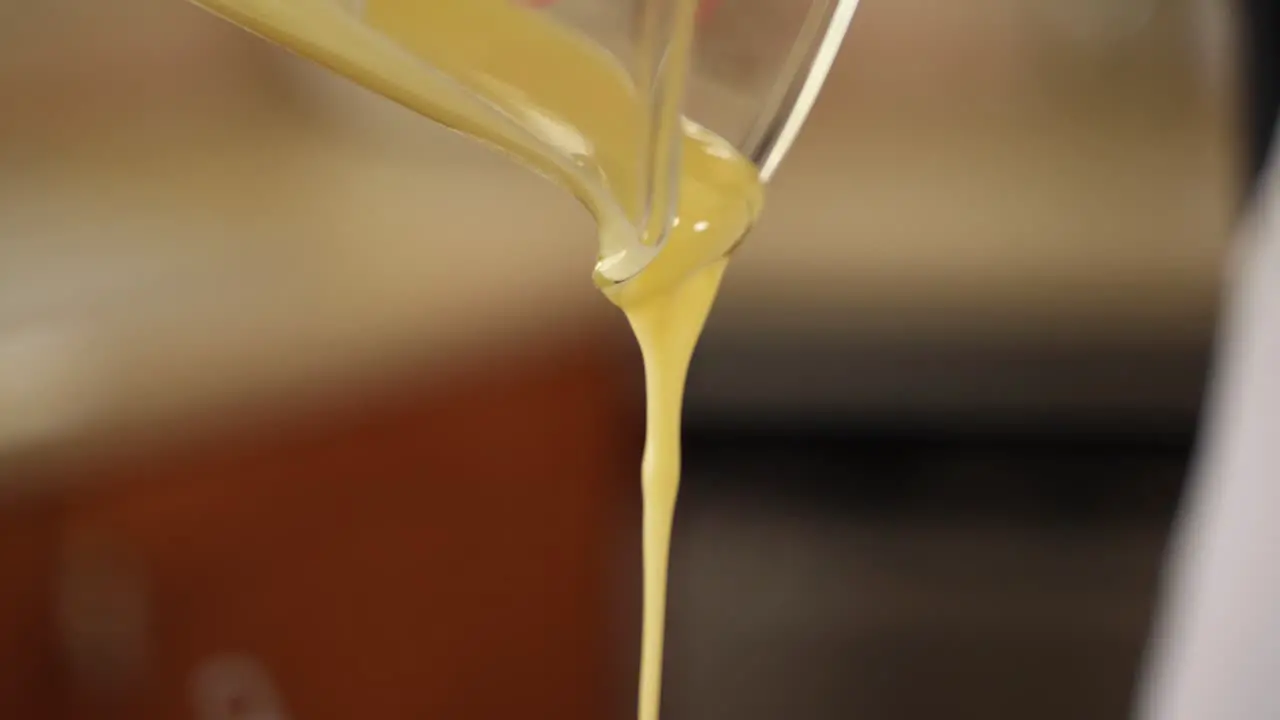 Pouring Liquid Butter from Glass Measuring Cup in Slow Motion with Copy Space