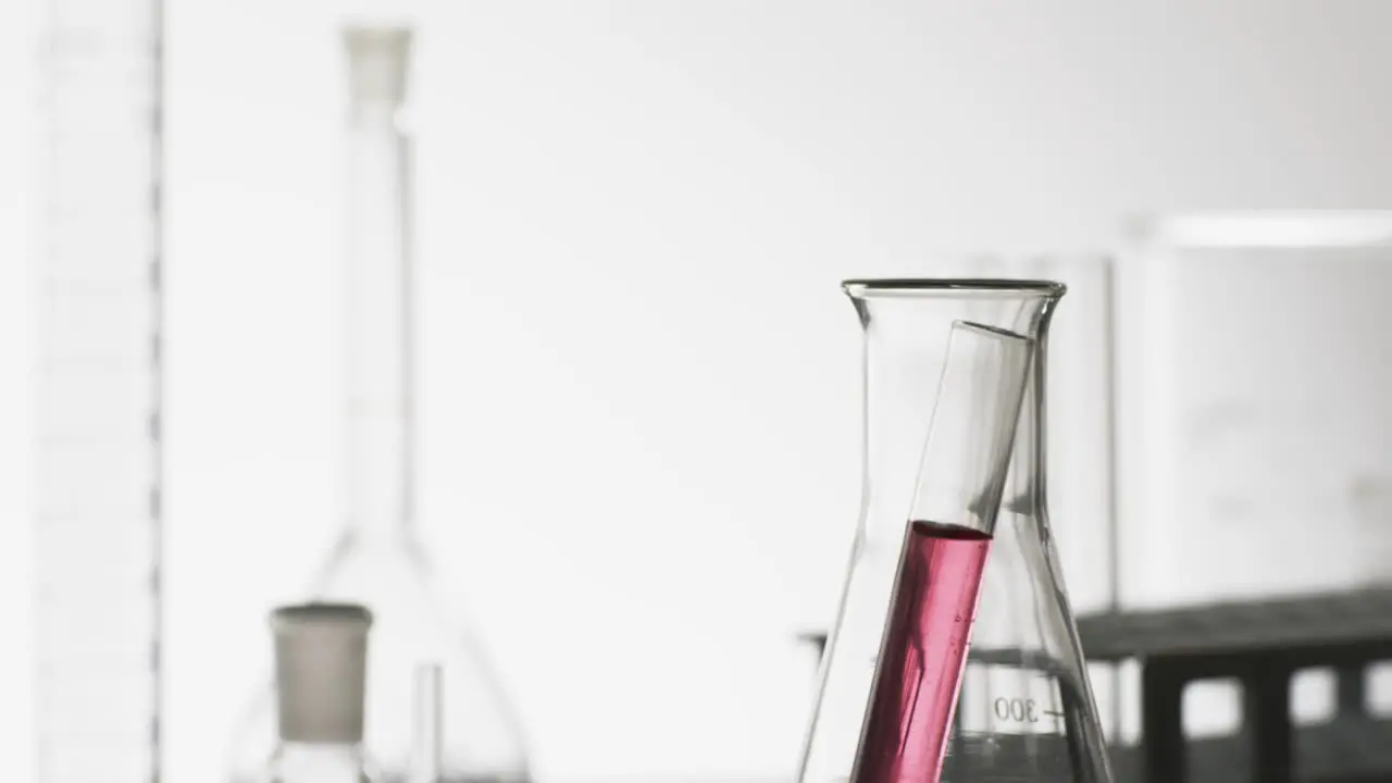 Video of glass laboratory test tube with pink liquid in beaker with copy space on white background