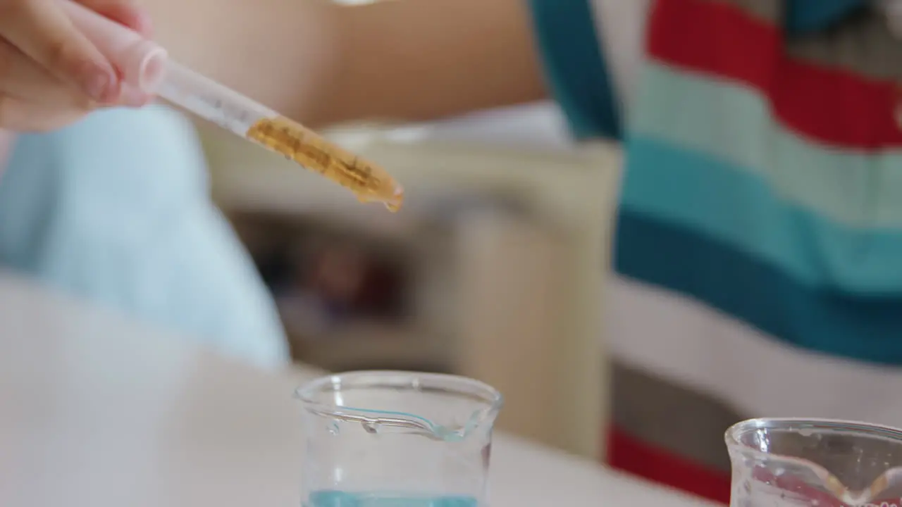 Girl wearing glasses using pipette and beaker