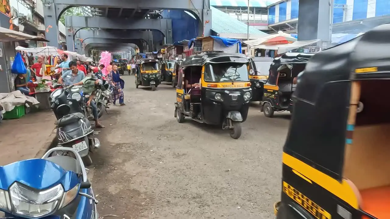 Mumbai India 20 August 2023 Auto rickshaw taxis motor bikes and people moving through a market in Mumbai India