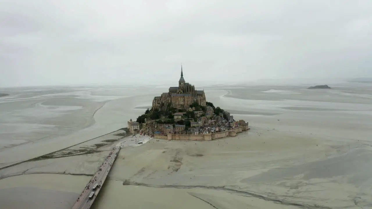 aerial drone view mont saint michel drone camera looking back there are many tourists coming back after seeing the castle