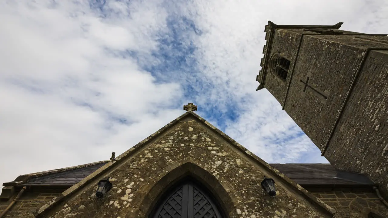 Time lapse of a historical medieval church with entrance door and tower in rural Ireland during the day with passing clouds in the sky