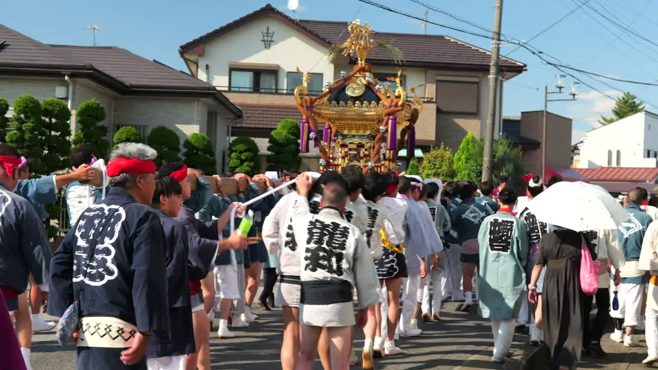 Japanese people carrying omikoshi portable shrine on hot day at small local summer matsuri festival