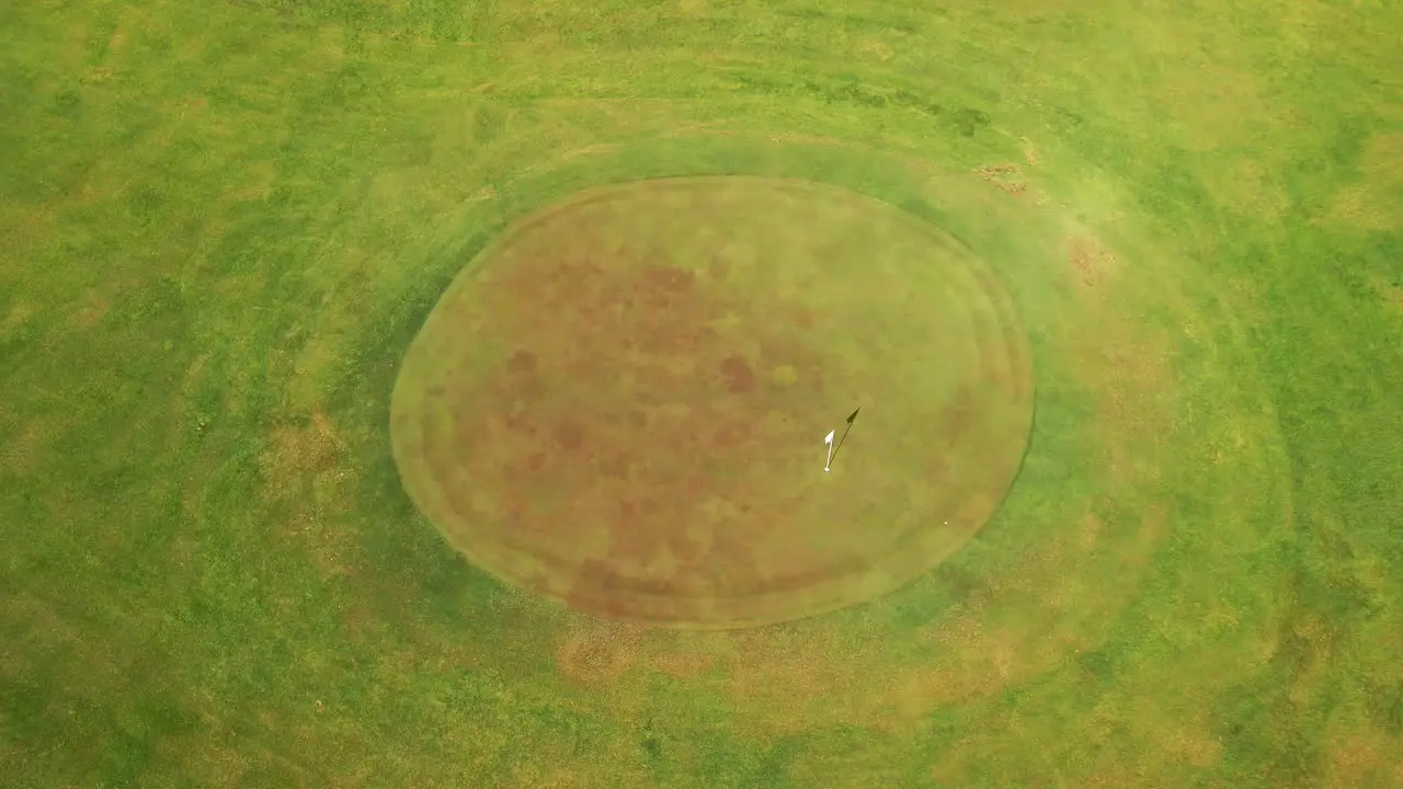 Cinematic drone shot of golf course green with flag blowing in the wind