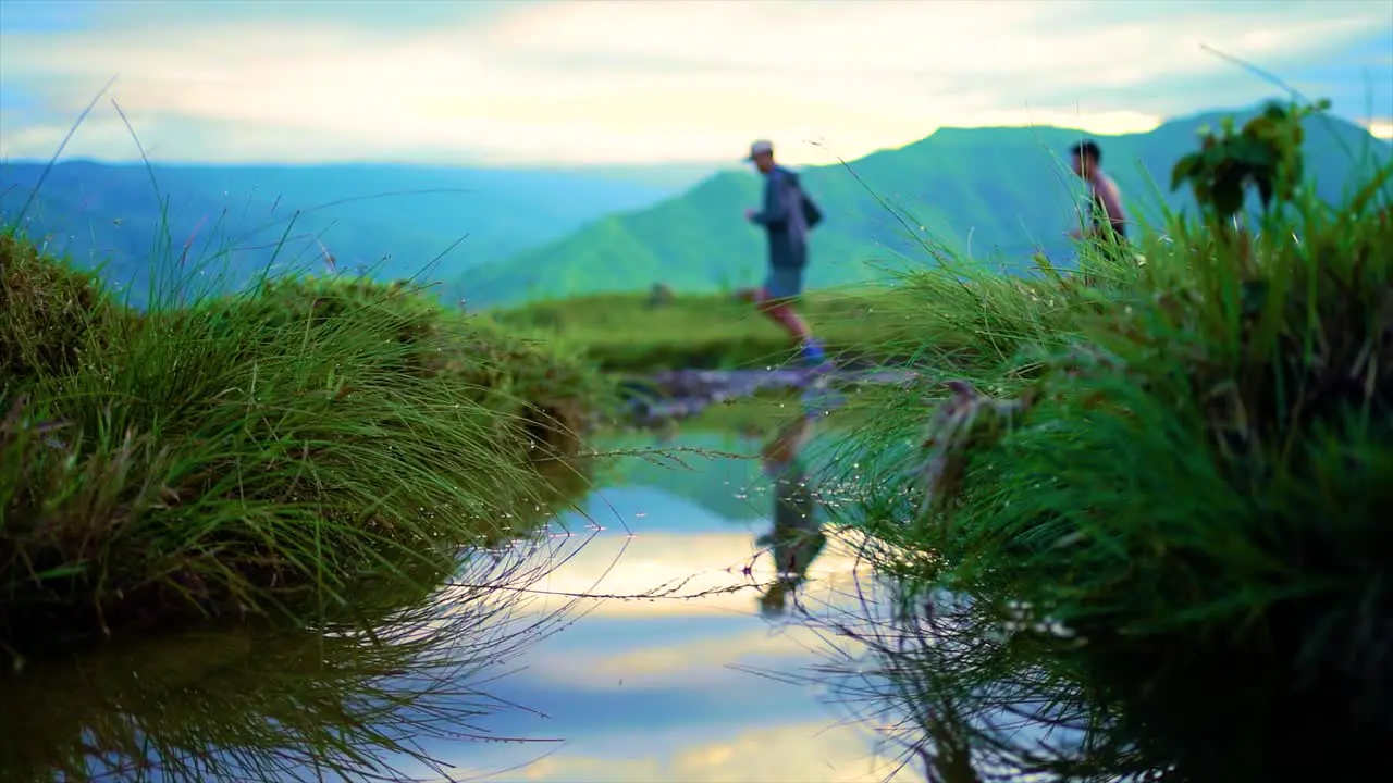 trail runners running to the mountains with a beautiful push in low angle puddle shot