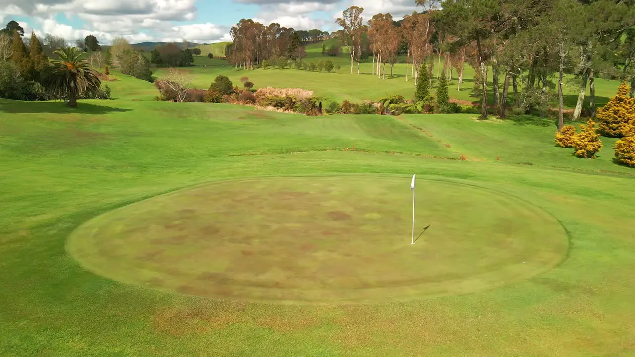 Golf course flag blowing in the wind on green