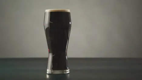 Pint Of Irish Stout In Glass Against Studio Background To Celebrate St Patricks Day 1