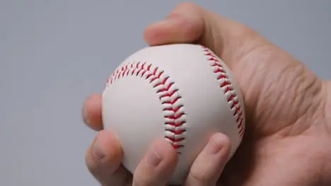 Close Up Shot Of Hand Throwing And Catching Baseball Ball Against Grey Background