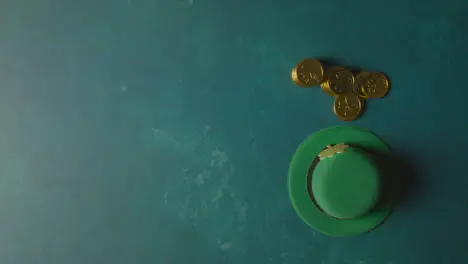 Overhead Studio Shot Of Green Leprechaun Top Hat And Hand Picking Up Gold Coins To Celebrate St Patricks Day