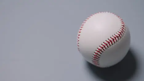 Close Up Shot Of Hand Picking Up Baseball Ball Against Grey Background