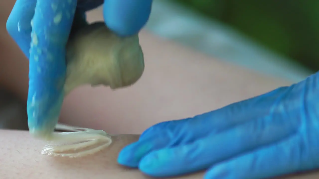 Close-up in the beauty salon master in gloves doing the procedure to remove the hair on the legs with a sugar mixture