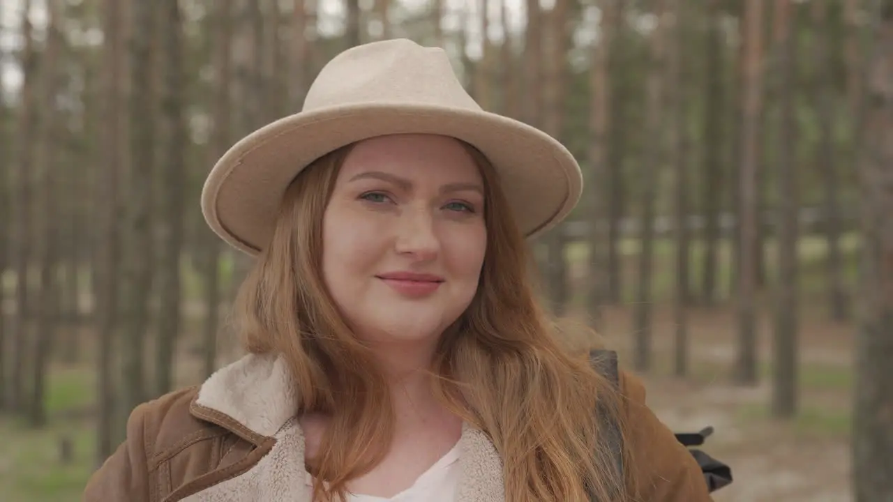 Portrait Of A Beautiful Red Haired Woman Wearing A Camel Hat In The Forest