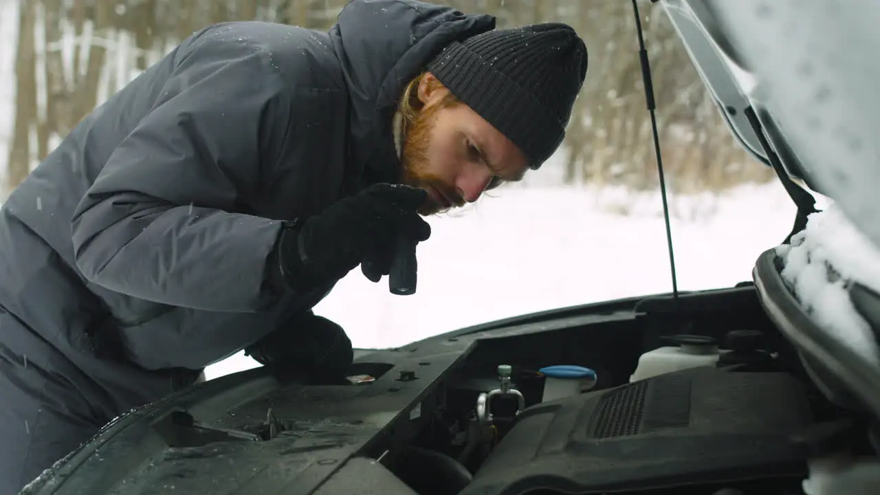 Man Stuck In The Winter Forest Holding A Torch And Checking His Car Engine Problem 1