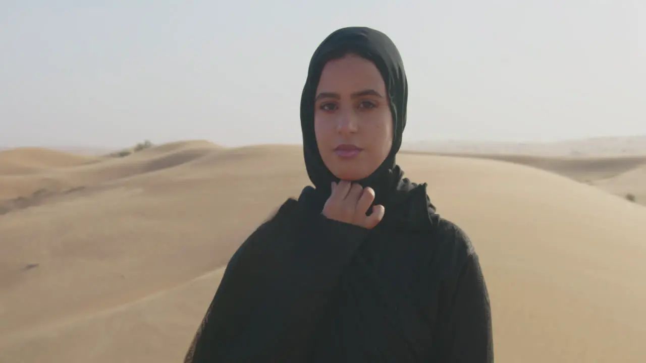 Portrait Of A Beautiful Muslim Woman With Hijab Looking At Camera In A Windy Desert