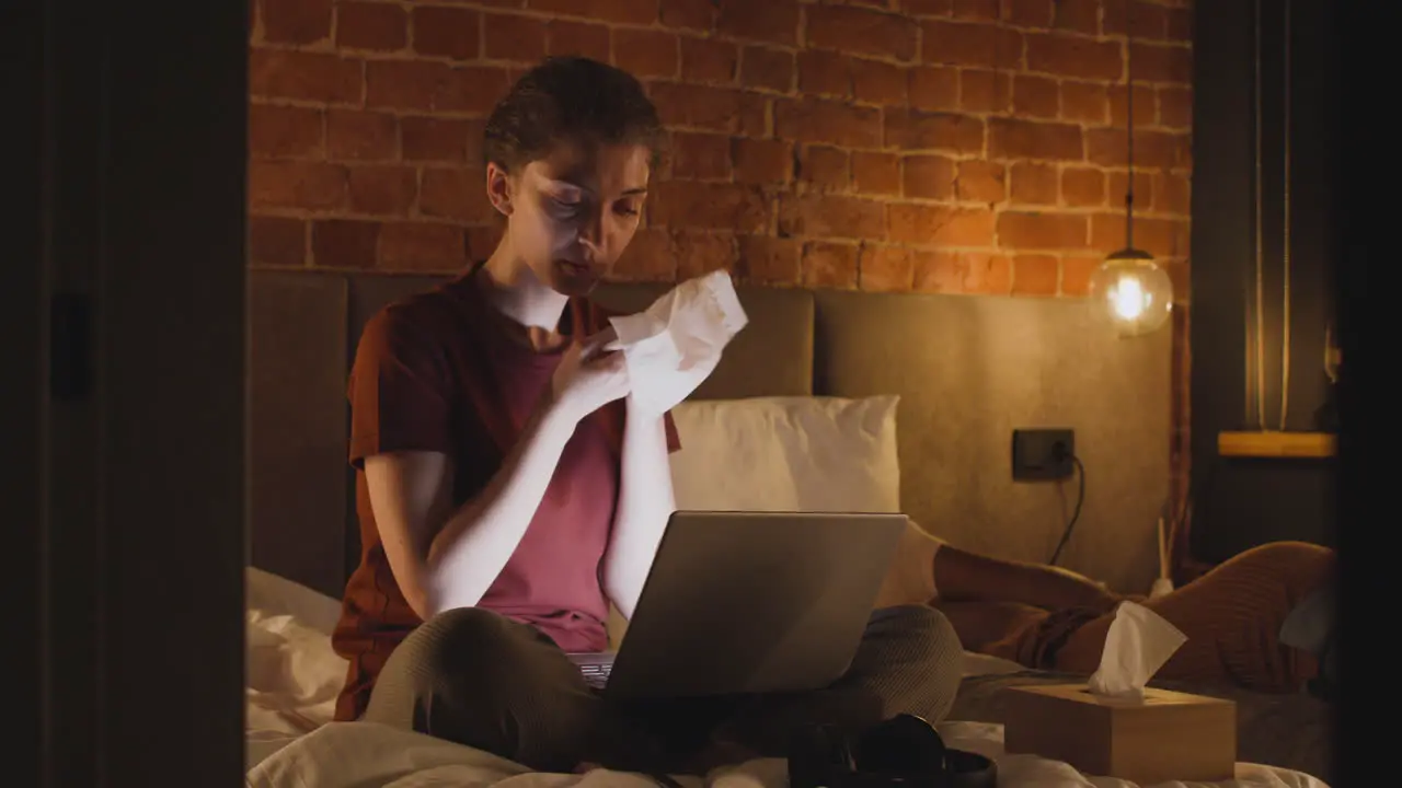 Girl Watching Videos On Laptop While Cleanig Her Face With A Paper Towel In Bedroom At Night