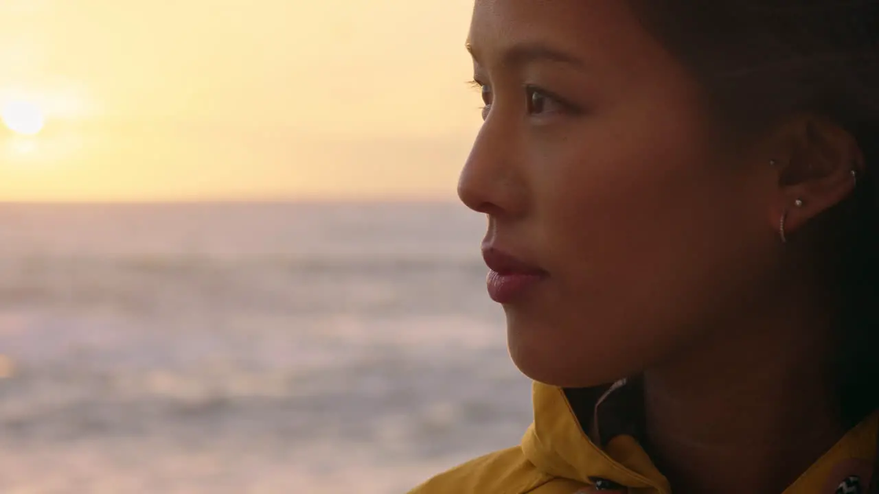 portrait of happy asian woman enjoying peaceful contemplation exploring carefree lifestyle relaxing on beach feeling positive at sunrise