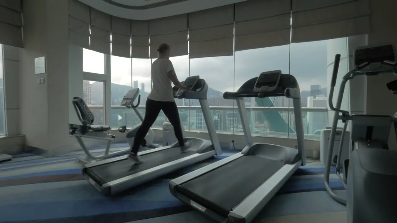 Clip of woman on the treadmill in fitness centre looking at window with cityscape Hong Kong China