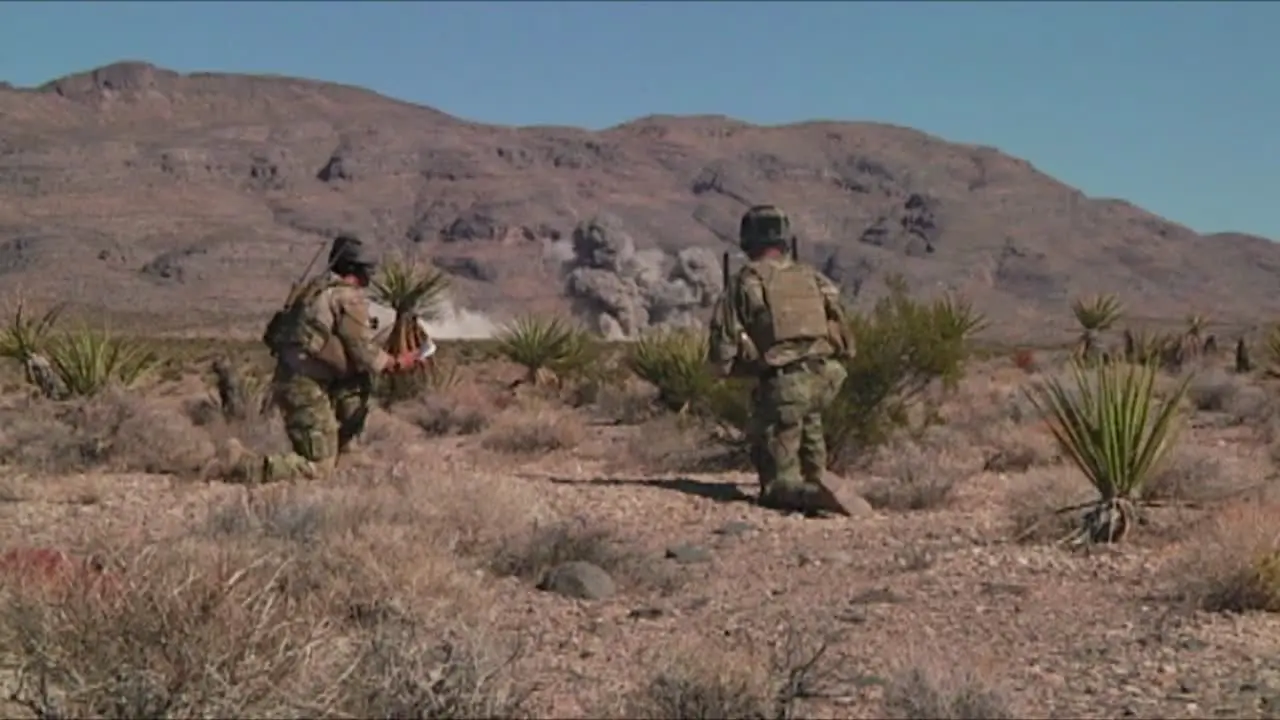 An F35 Lightning Bombs Targets In The Desert While Soldiers Look On