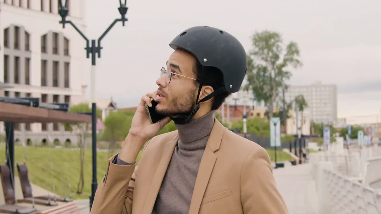 Junger Amerikaner In Formeller Kleidung Und Helm Der Einen Anruf Auf Dem Handy Hat Während Er Auf Dem Fahrrad In Der Stadt Sitzt 1