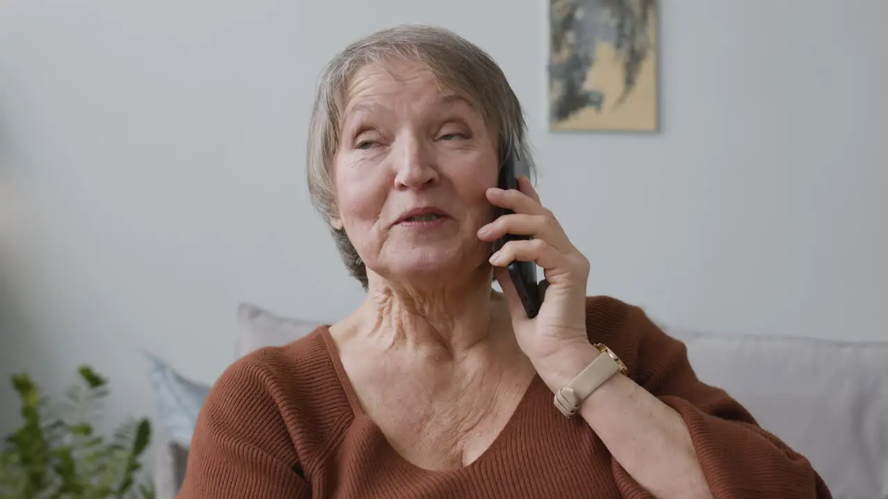 Anciana Llamando Por Teléfono Inteligente Sentada En Casa