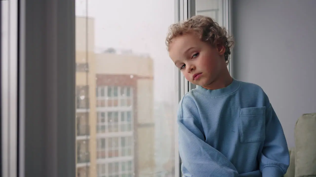 Un Niño Pensativo De Cuatro Años Está Viendo Caer La Nieve Desde La Ventana De Su Habitación En Un Acogedor Apartamento Moderno