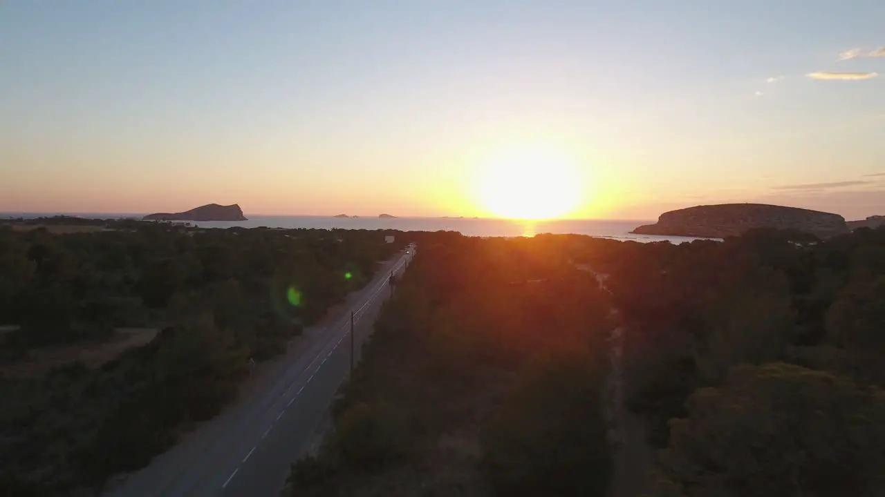 Drone shot of a road cutting through trees to the coast