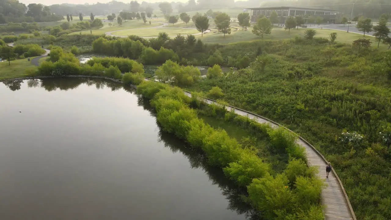 Aerial footage of person jogging along trail in a beautiful park