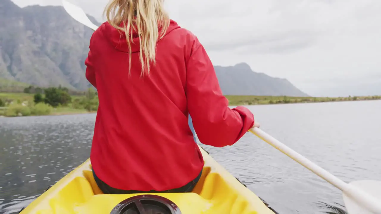 Caucasian woman having a good time on a trip to the mountains kayaking on a lake holding a paddle