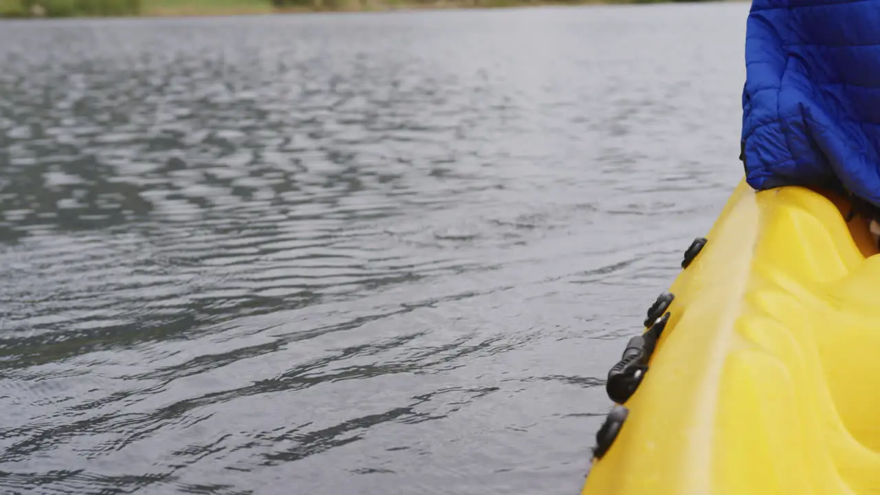 Caucasian man having a good time on a trip to the mountains kayaking on a lake holding a paddle