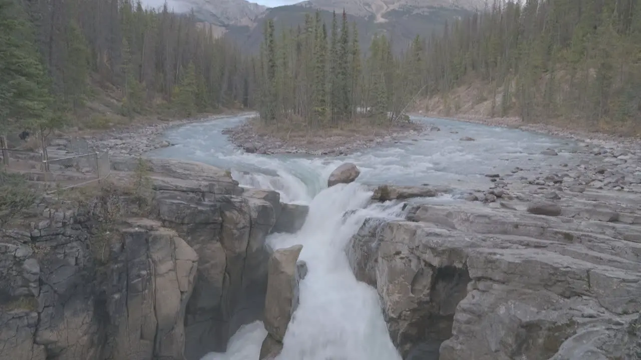 A picturesque waterfall surrounded by a lush forest and mountains