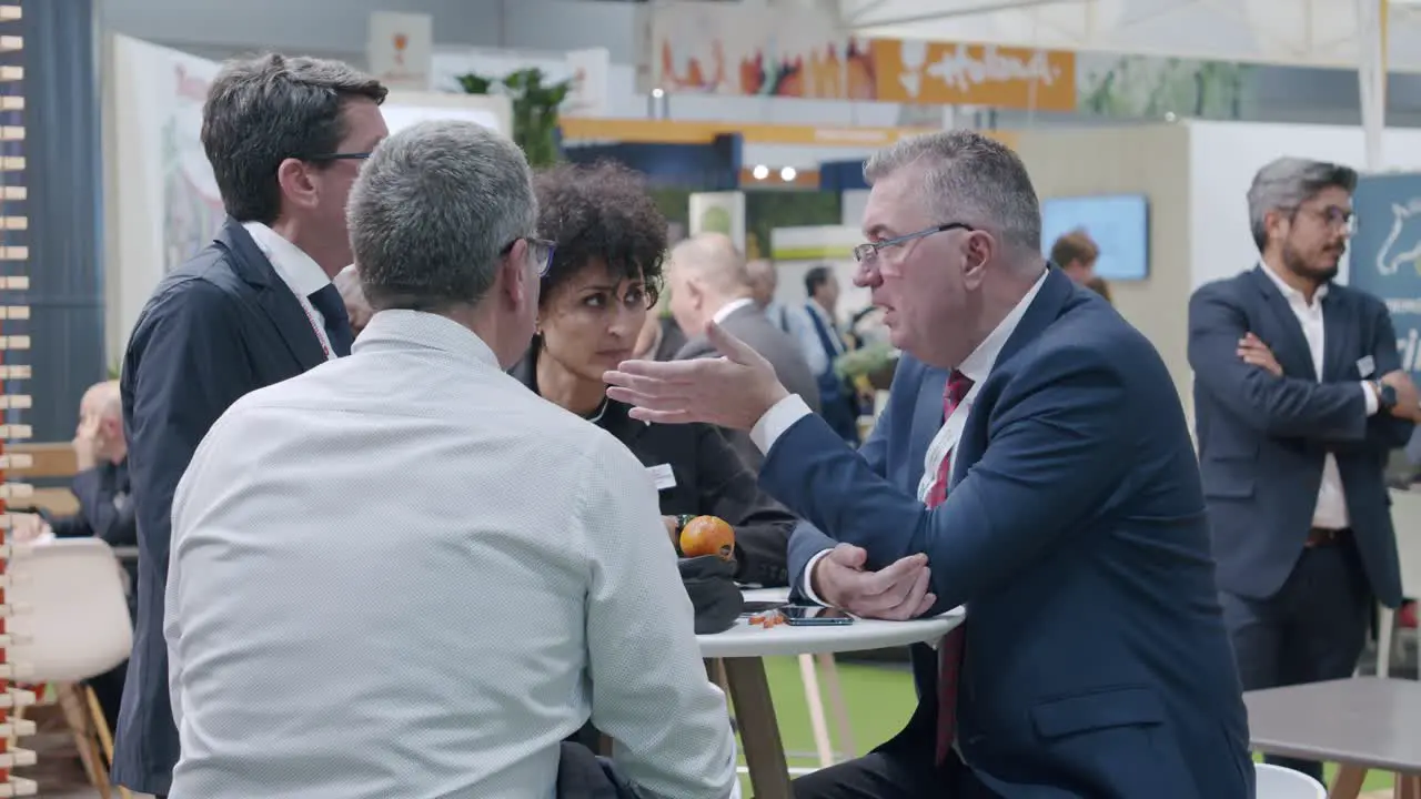 Group of co-workers sitting discussing around desk trade show Madrid Spain