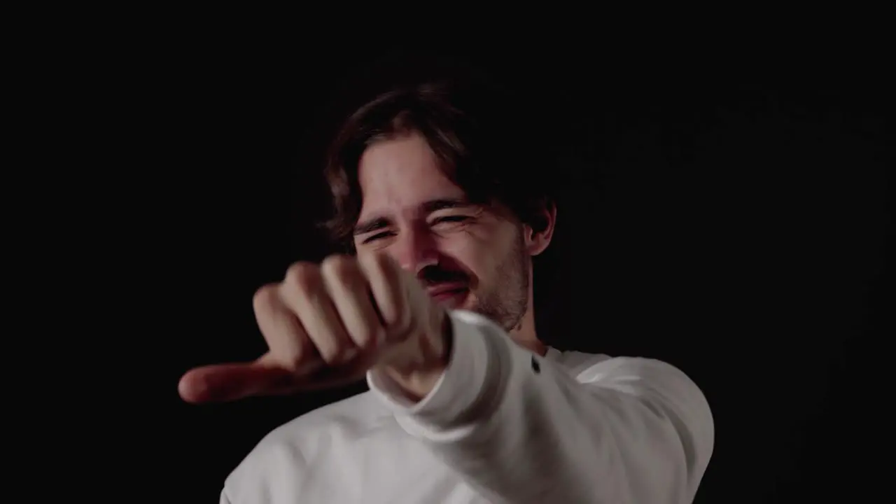 Trendy Young Man unsure thumb up and down gesture close black background