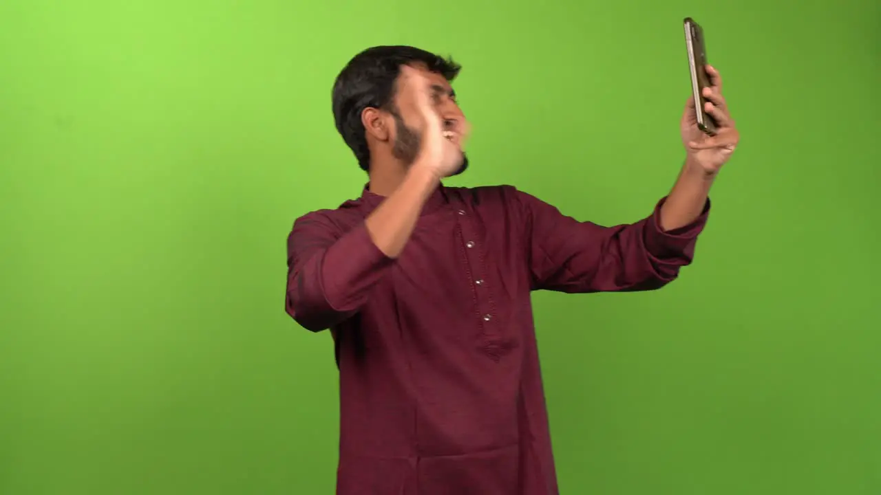 Handsome man calling and talking with friends on smartphone isolated on green screen