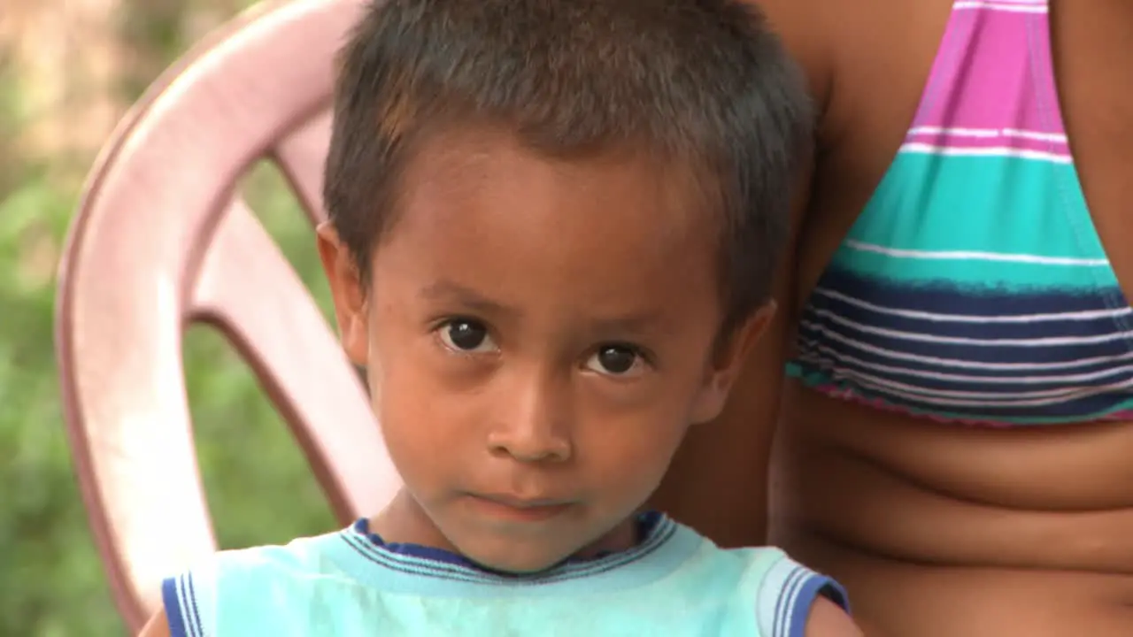 a young Amazonian native boy waving next to his mother