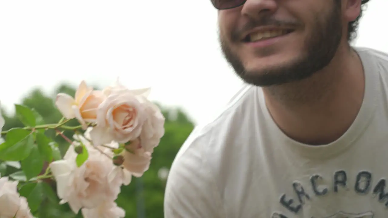 Close up Panning shot of Guy with Glasses smelling Roses