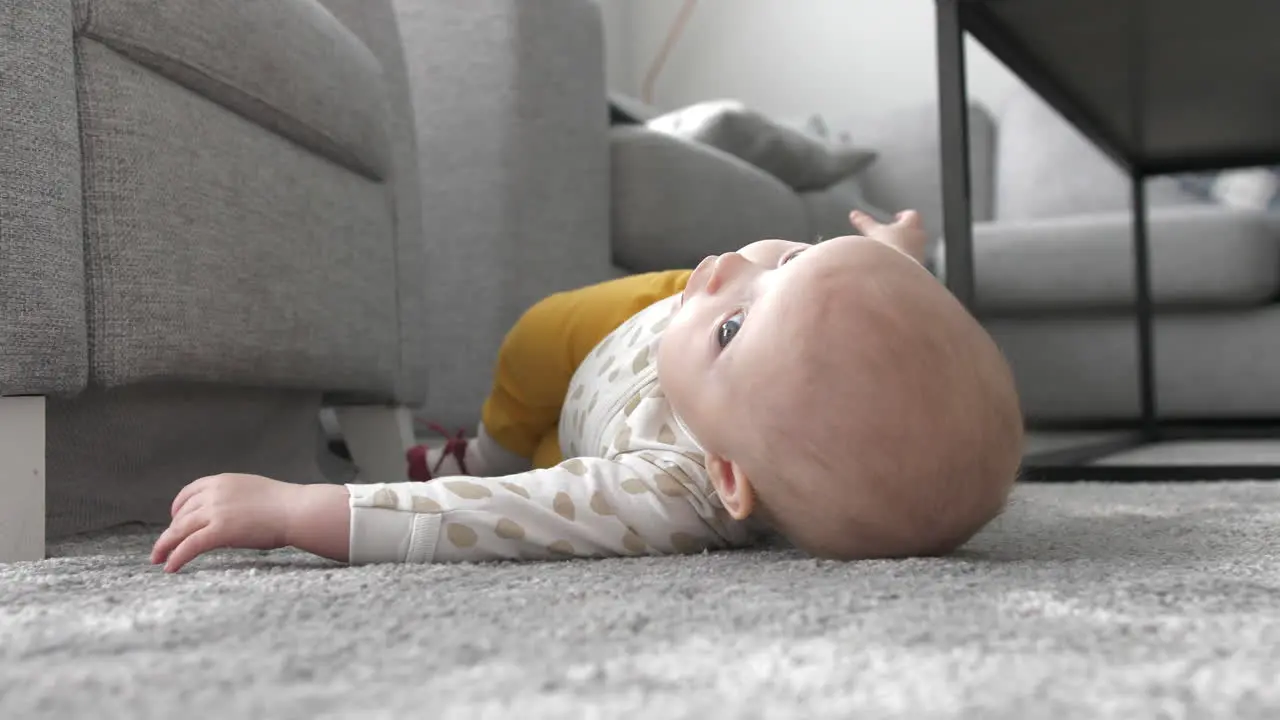 baby girl learning to roll over on livingroom carpet