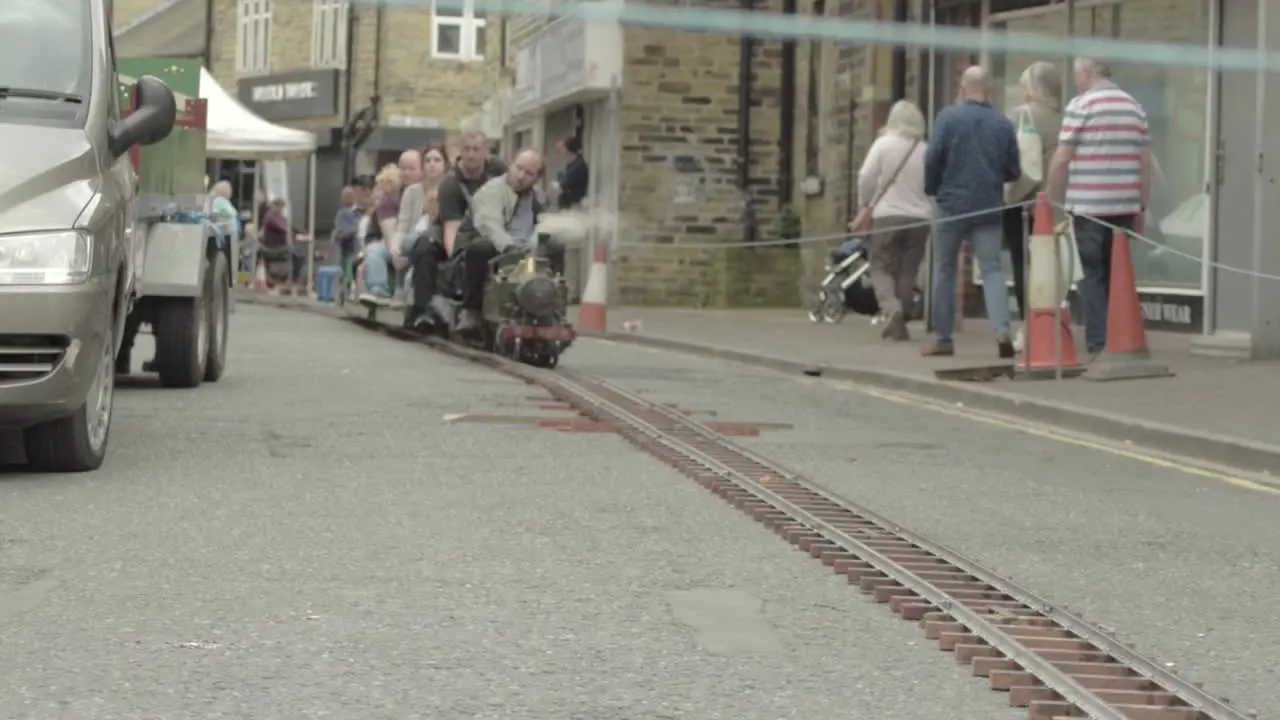 Adults on a mini steam train riding backwards in town center