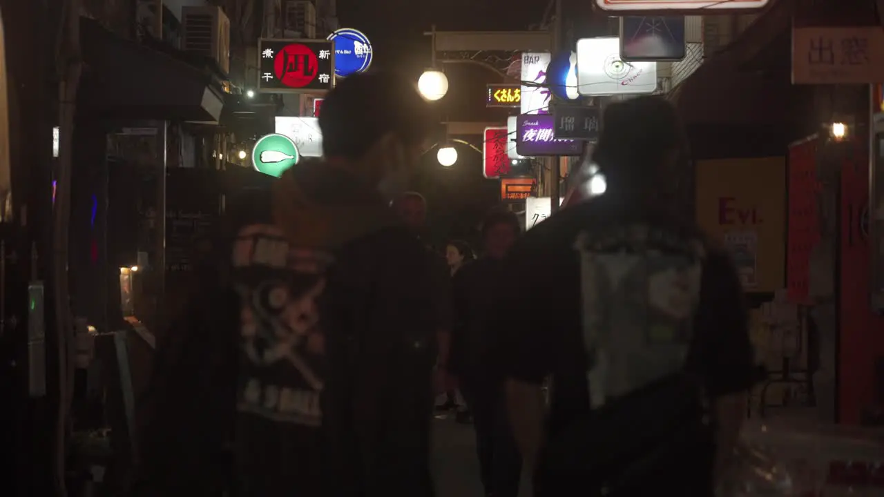 View Looking Down Along Golden Gai Street In Shinjuku At Night With People Walking Past