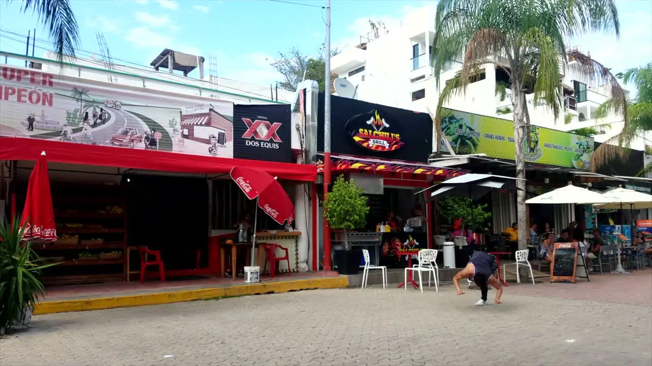 Young Man In Singlet Doing Flips And Breakdancing Tricks On The Boardwalk In Mexico In Front Of Shops