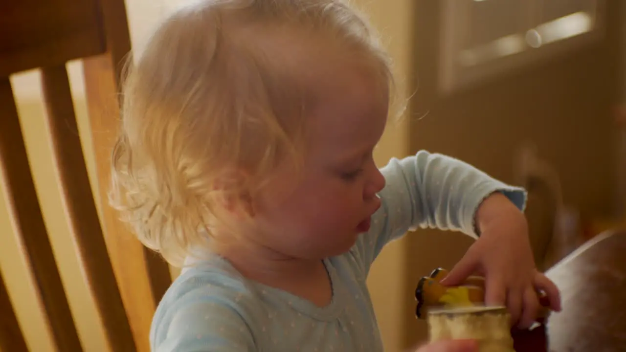 Adorable two-year old girl playing with her toys at the kitchen table close up