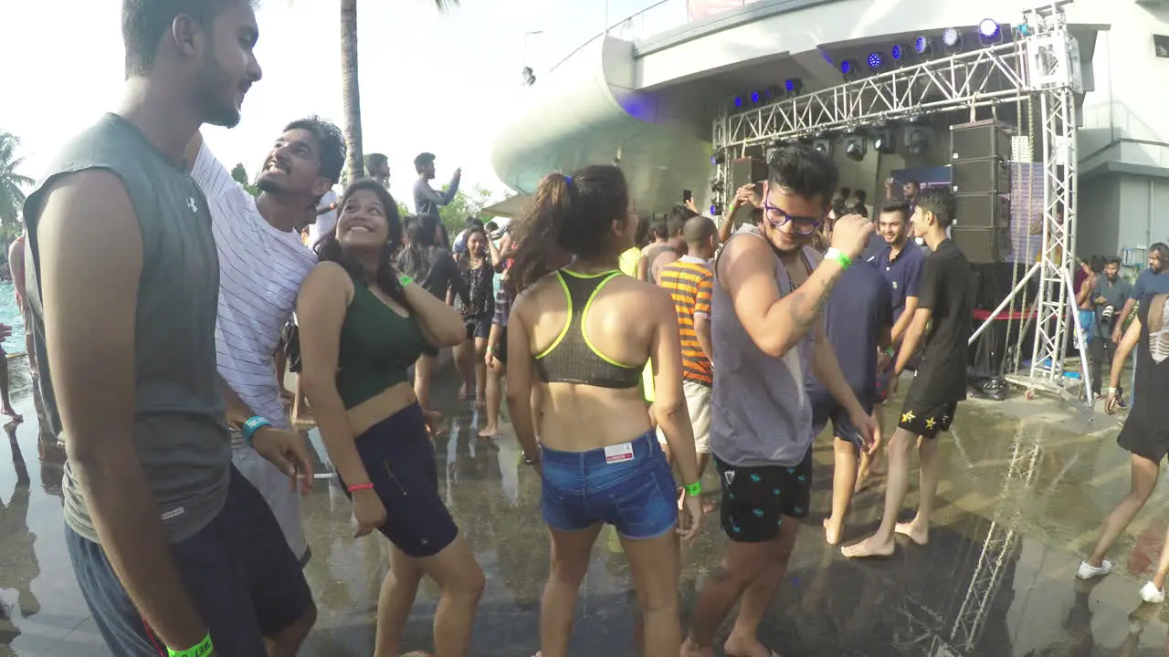 Beautiful girls of India enjoying an outdoor pool party by dancing and grooving to the music with their friends as water splashes by